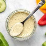 glass jar of vegan ranch dressing surrounded by colorful vegetables
