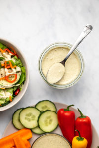 glass jar of vegan ranch with salad and veggie tray