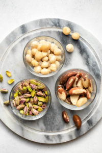 glass bowls of macadamia nuts, pistachios, and brazil nuts