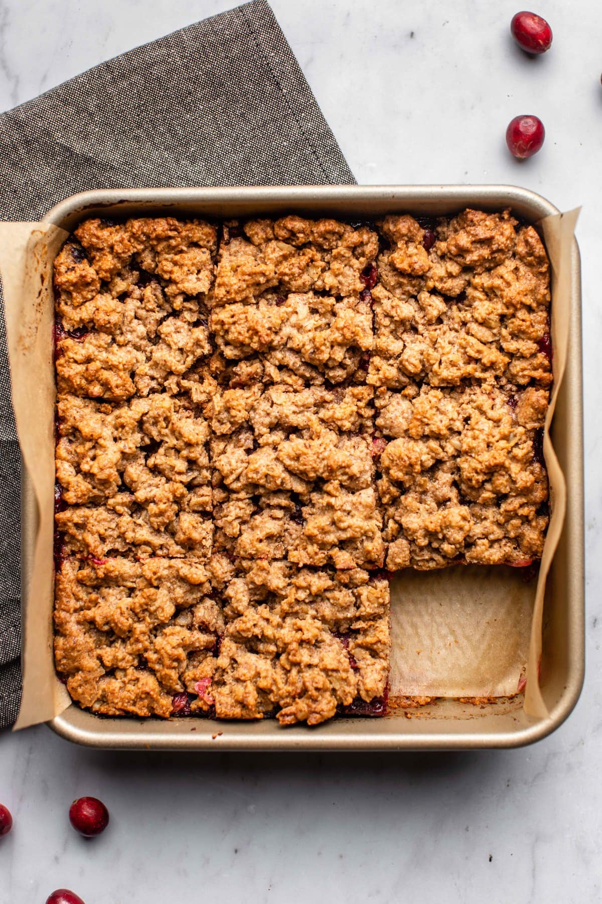 cooked cranberry orange crumble bars in gold baking pan sliced into 9 pieces with one slice taken out