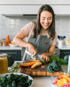 caitlin in kitchen chopping carrots on wooden cutting boar
