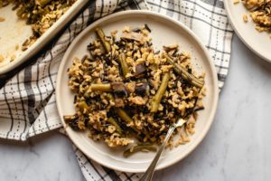 green bean and mushroom casserole on white plate with marble background