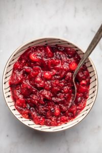 cranberry sauce in white bowl with black stripes on marble background