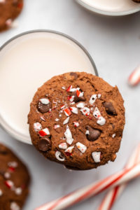 double chocolate peppermint cookie balancing on glass of milk with candy canes in the background