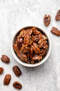 candied pecans in small white bowl on marble background