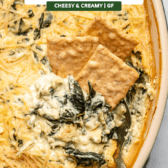 crackers scooping baked spinach artichoke dip