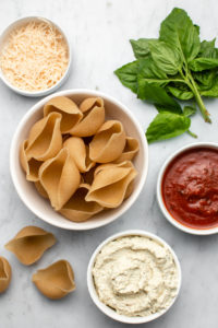 ingredients for stuffed shells in small white bowls on marble background