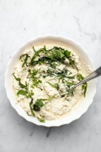 white bowl of vegan ricotta cheese with basil mixed in 