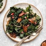 winter kale salad on small speckled white plate on textured blue background
