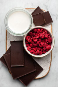 ingredients for chocolate raspberry truffles on white speckled ceramic tray