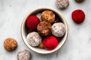 bowl of chocolate raspberry truffles coated in various powders on marble background