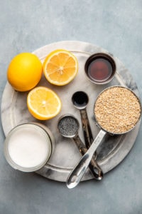 ingredients for lemon poppyseed oatmeal in measuring cups on round marble cutting board