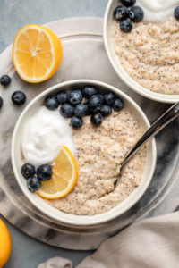 lemon poppyseed oatmeal with blueberries and coconut yogurt in white bowl on marble background