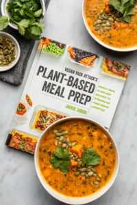 bowl of smoky sweet potato soup on top of plant based meal prep cookbook