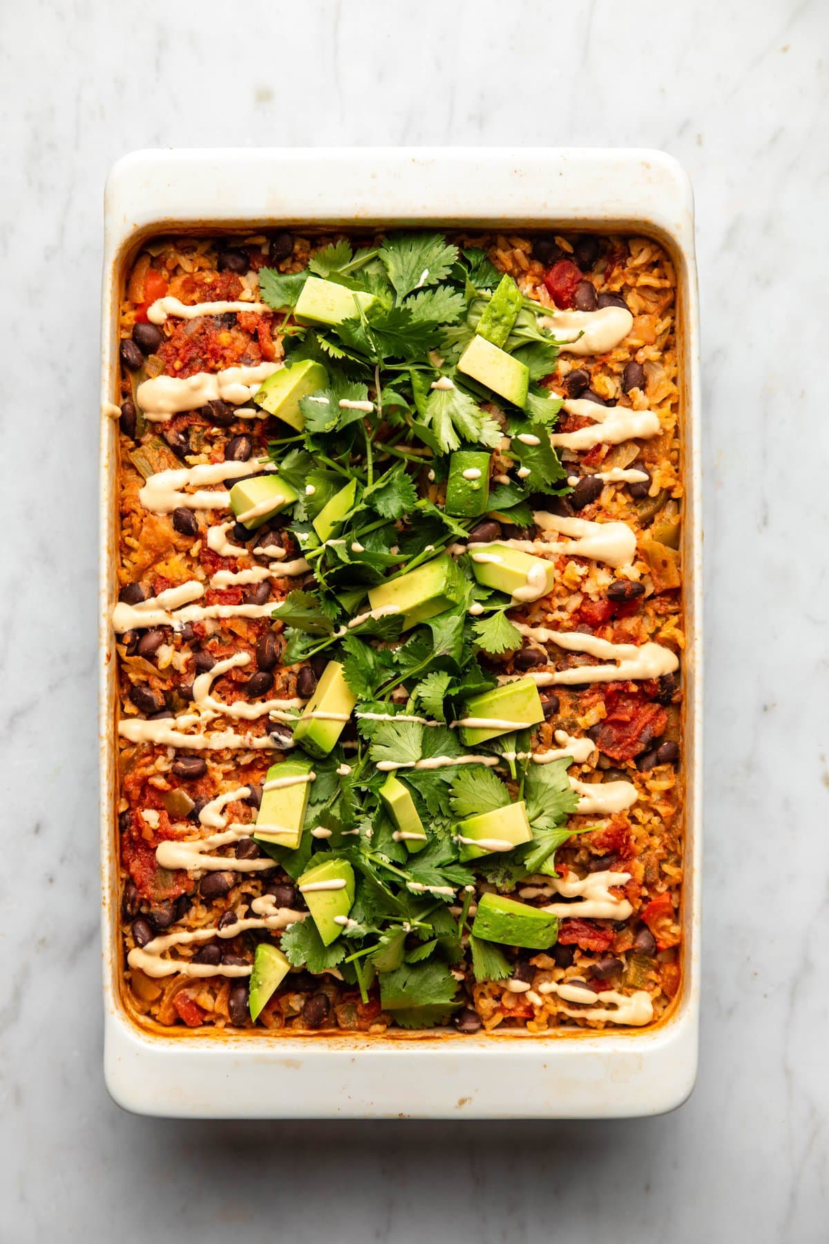 southwestern black bean casserole topped with cilantro, avocado, and chipotle mayo