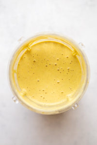 curry tahini dressing blended in bullet blender container on white background