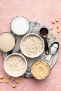 ingredients for cashew butter blondies on marble serving tray and pink background
