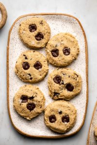 cooked chickpea chocolate chip cookies on white speckled tray on marble background