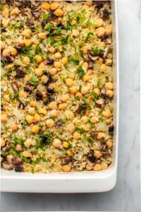 cooked chickpea rice casserole topped with black pepper and parsley on marble background
