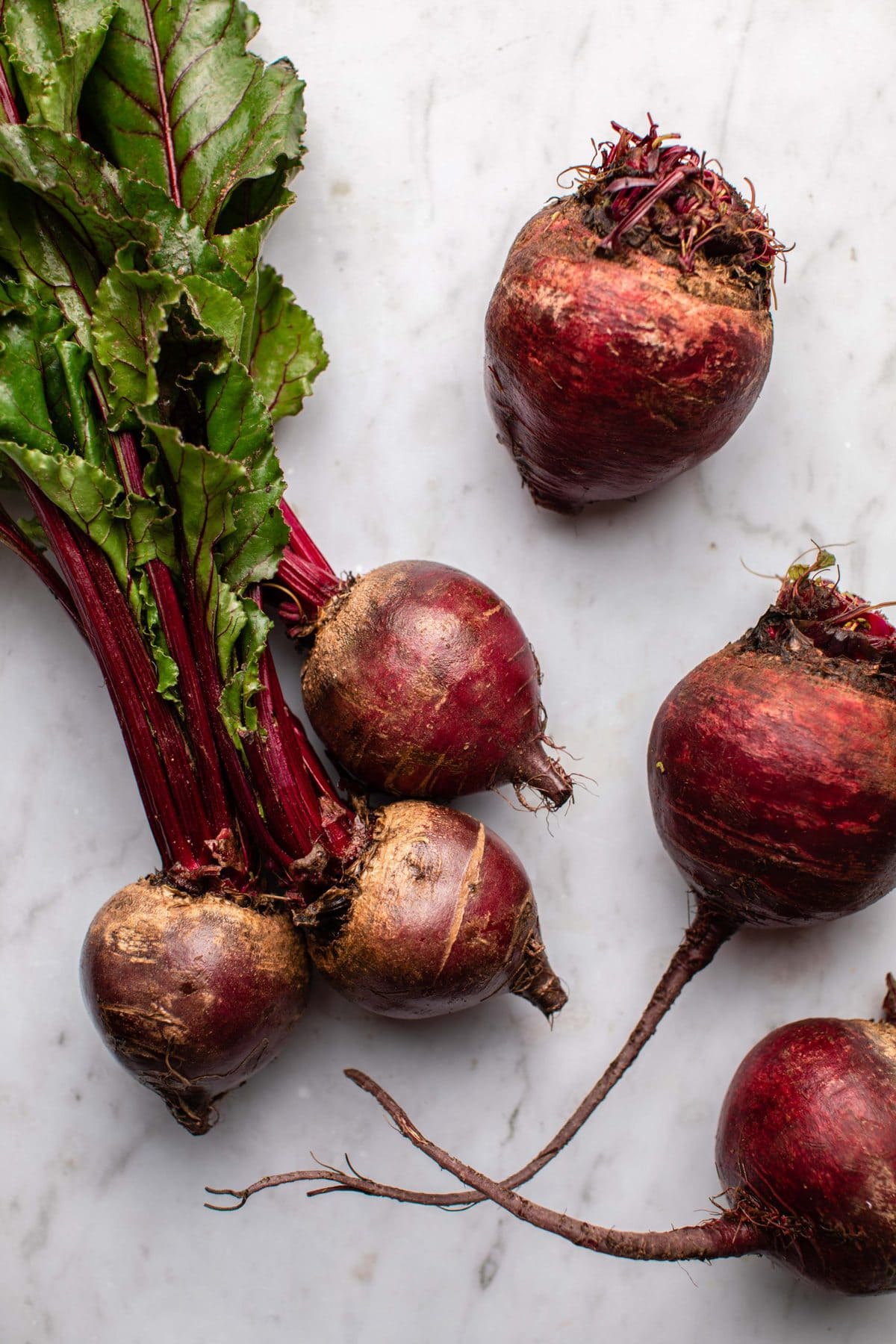 beets with greens and beet bulbs on marble background