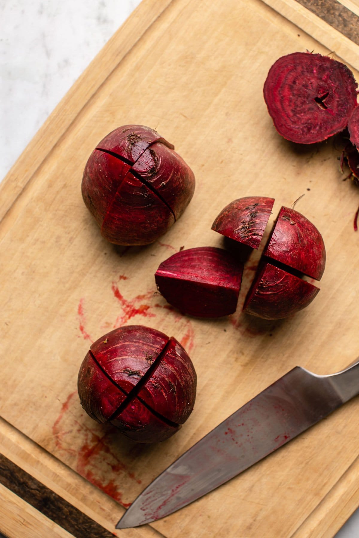 beets cut into quarters on wood cutting board
