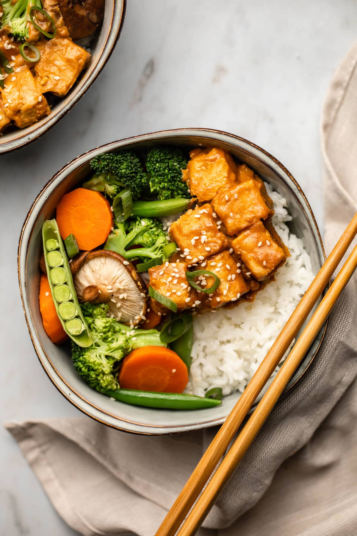 peanut tempeh bowls with steamed vegetables and rice on marble background