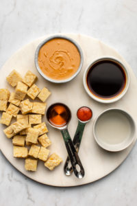 ingredients for stovetop peanut tempeh on round white stone cutting board