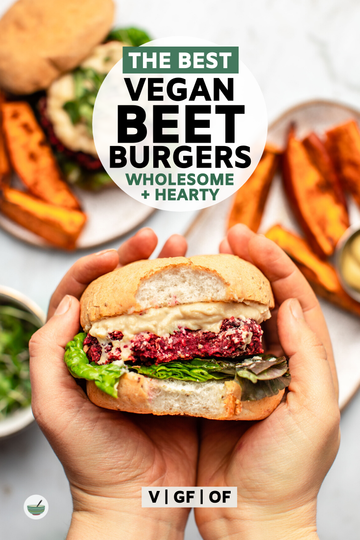 hands holding beet burger on marble background with side of sweet potato fries