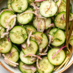 cucumber dill salad with red onions and mustard in large bowl on marble background