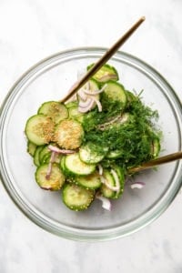ingredients for cucumber salad in glass bowl before mixing