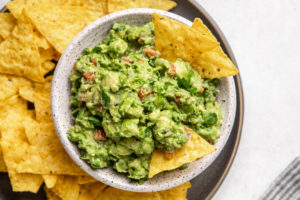 white bowl of guacamole with yellow corn chips