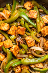 close up photo of black pepper tofu with green pepper and onion