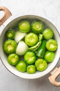 tomatillos, onion, and jalapeños in pot of water before boiling