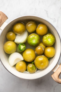 tomatillos, onion, and jalapeños in pot of water after boiling