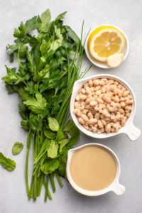 ingredients for creamy white bean dip in small white bowls on grey background