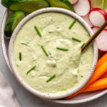 creamy white bean dip with spring herbs in gray bowl topped with chives and served with crudités