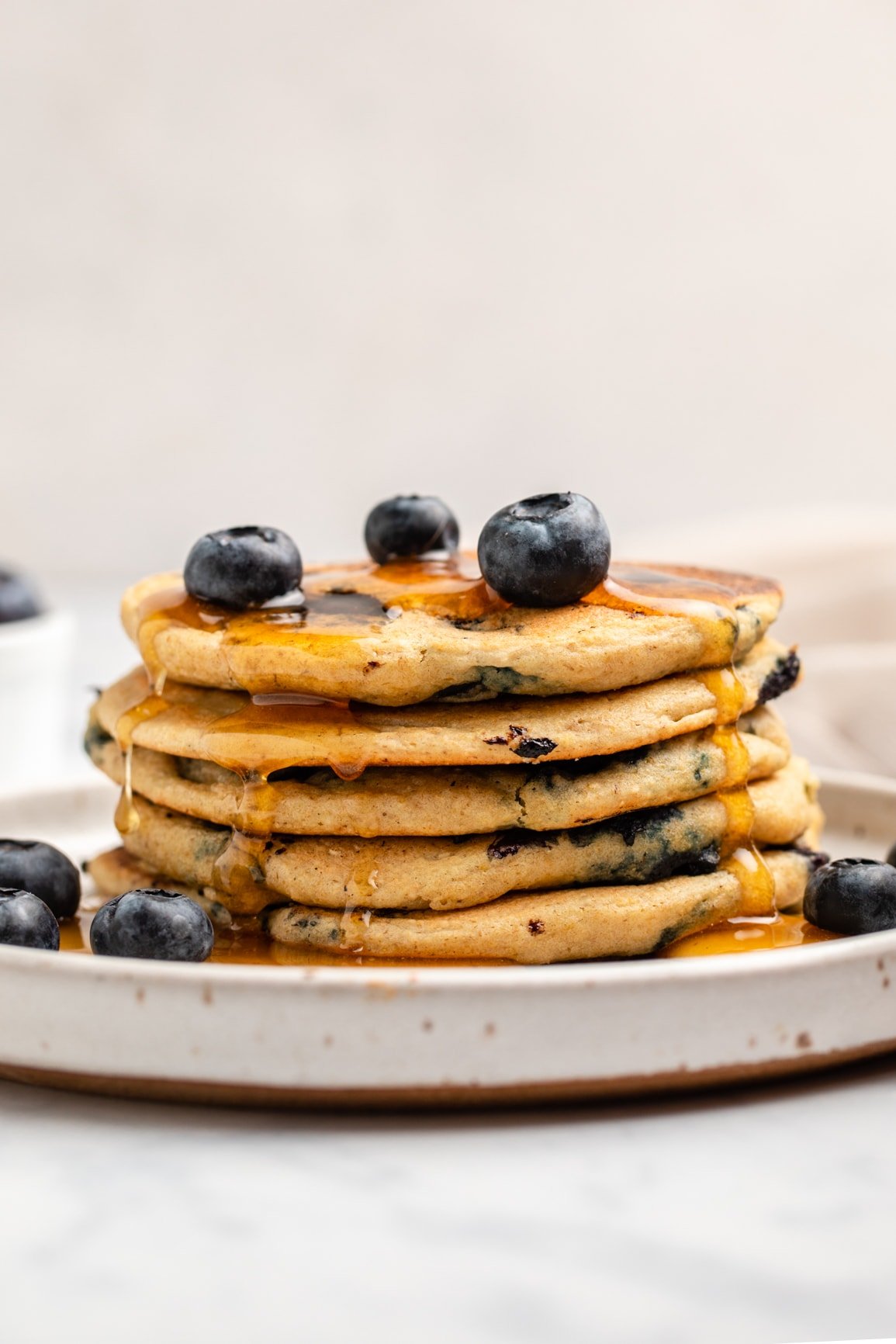 stack of blueberry pancakes with fresh blueberries and maple syrup
