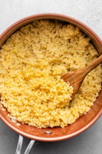 photo of cooked millet in pot with wooden spoon