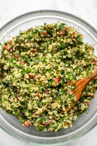 mixing bowl of cooked millet mixed with vegetables for millet tabbouleh