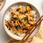 Vegan Sesame Chicken in white bowl topped with sesame seeds and green onion