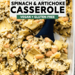 navy spoon scooping spinach & artichoke casserole out of white baking dish