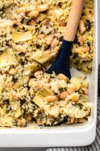 spoon scooping spinach & artichoke casserole out of baked dish