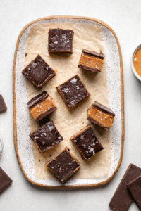 sliced almond butter bars on white serving tray topped with flaky sea salt