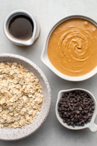 ingredients for peanut butter energy bites in white bowls on white background