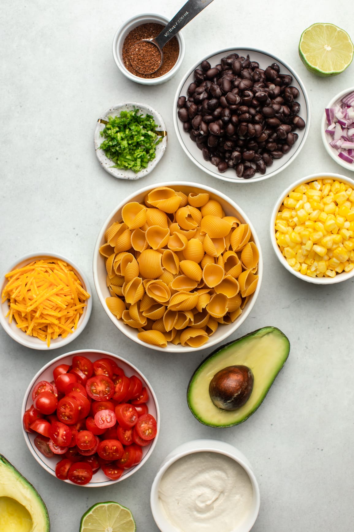 ingredients for vegan taco pasta salad in small white bowls on grey background