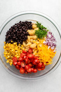 vegan taco pasta salad recipe ingredients in large glass bowl before mixing