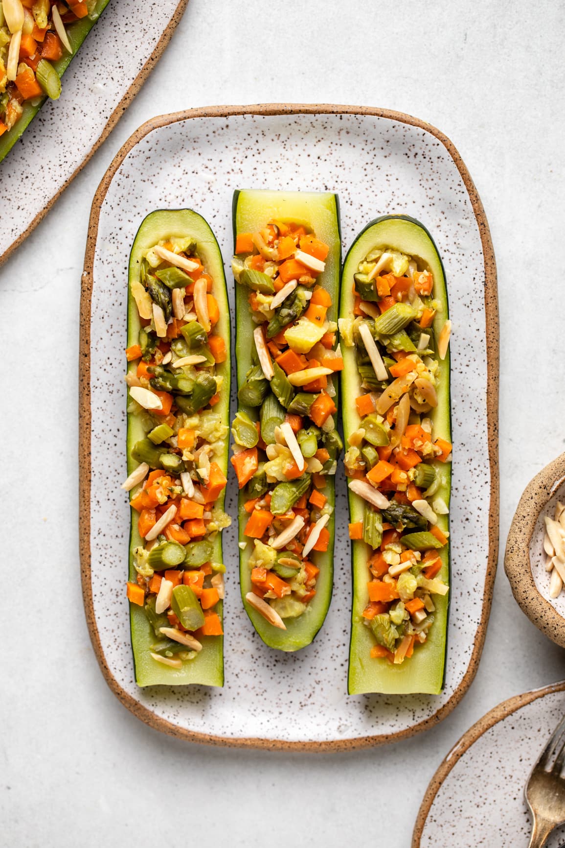 cooked stuffed zucchini topped with toasted almonds on white serving dish