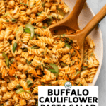 large white bowl of buffalo cauliflower pasta salad with two wooden serving spoons