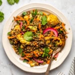 curried lentil salad topped with fresh cilantro on white plate with spoon and striped napkin