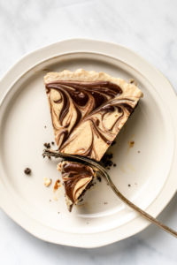 slice of peanut butter cup pie on white plate with fork slicing through it